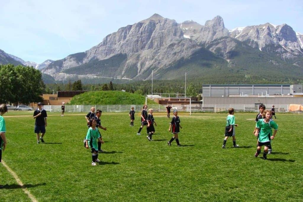 Match de football des enfants du printemps devant les montagnes Three Sisters Canmore Alberta. Sports les plus populaires au Canada.