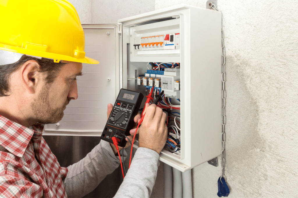Un électricien teste une boîte de câblage pour gagner son salaire d'électricien au Canada