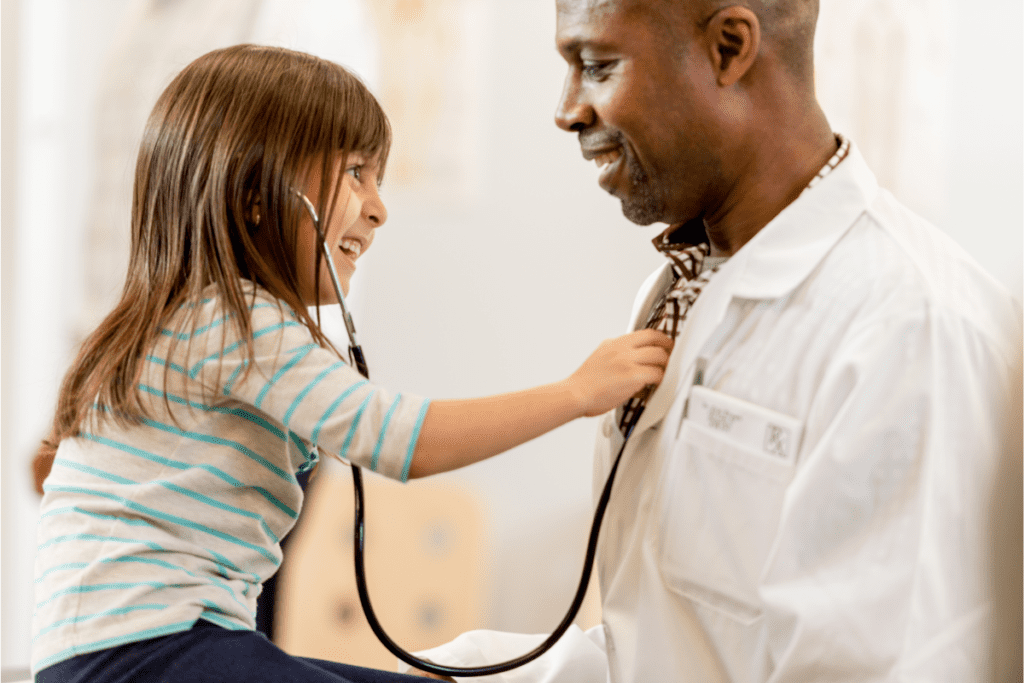 Une jeune fille joue avec le stéthoscope du médecin après que sa famille a demandé une carte de santé du Yukon au Canada
