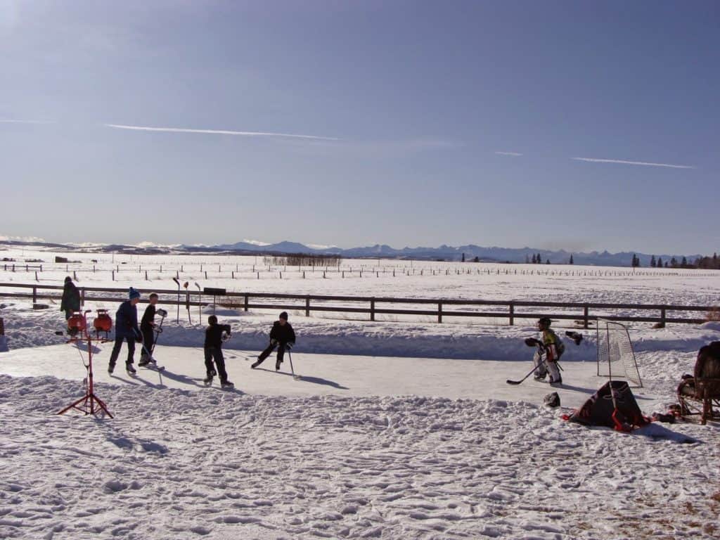 Los niños juegan hockey sobre hielo en una pista al aire libre casera en Black Diamond Canada, una de las mejores ciudades pequeñas de Alberta