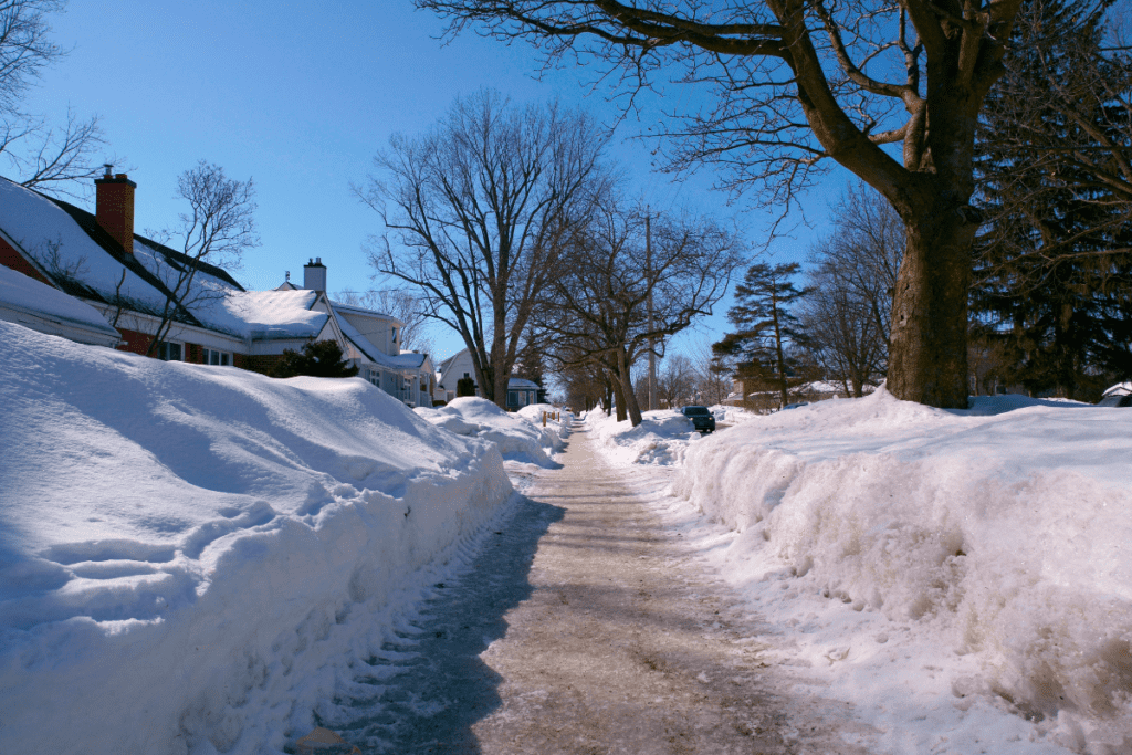 Invierno en uno de los mejores barrios de Ottawa La nieve se acumula a varios pies de altura a los lados de una pequeña carretera
