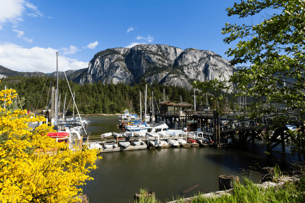 Une vue de bateaux dans un port dans les belles montagnes entourant la ville de Squamish comme exemple des avantages et des inconvénients de vivre à Squamish Bc Canada
