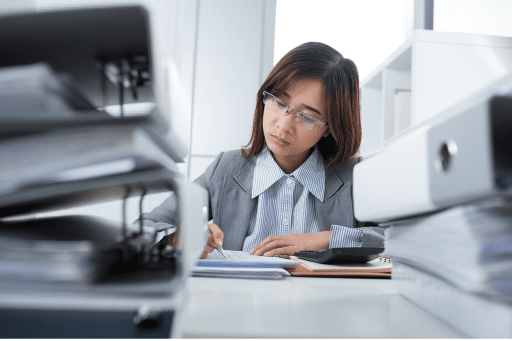 A Worker At Her Desk Surrounded By Large Files Earns Her Bookkeeper’s Salary In Canada