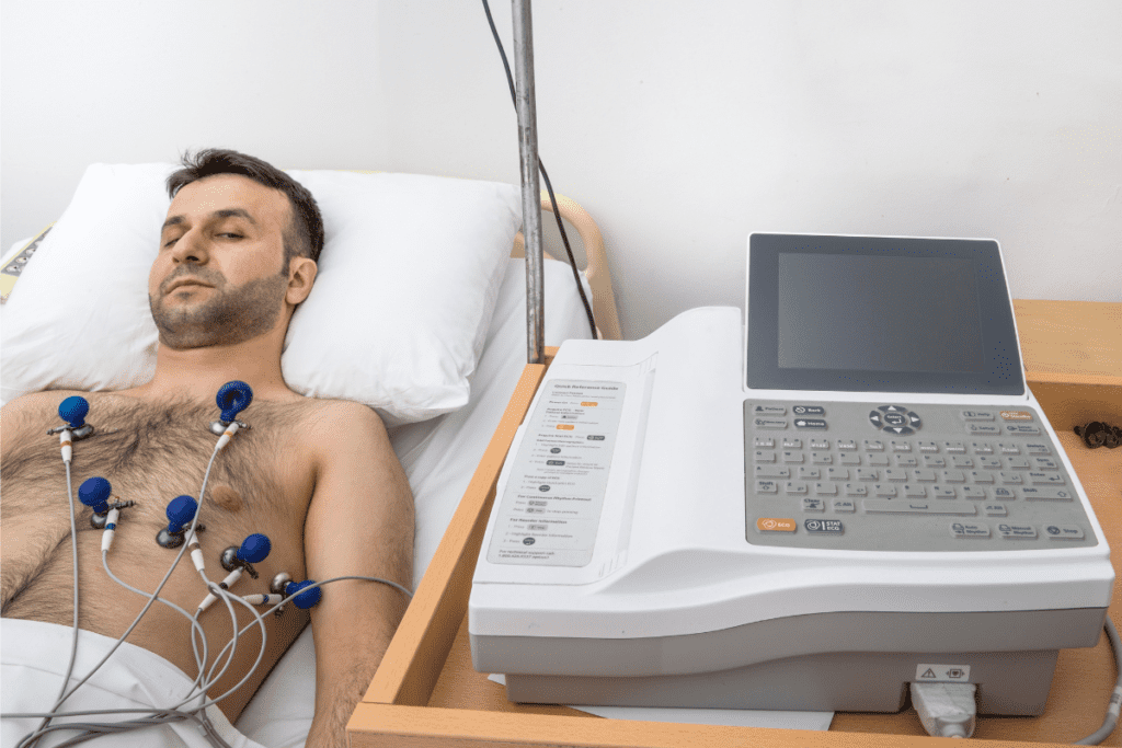 A Man Lies On A Hospital Bed Wired Up To An Electrocardiogram Machine Cardiology Technologist'S Salary In Canada