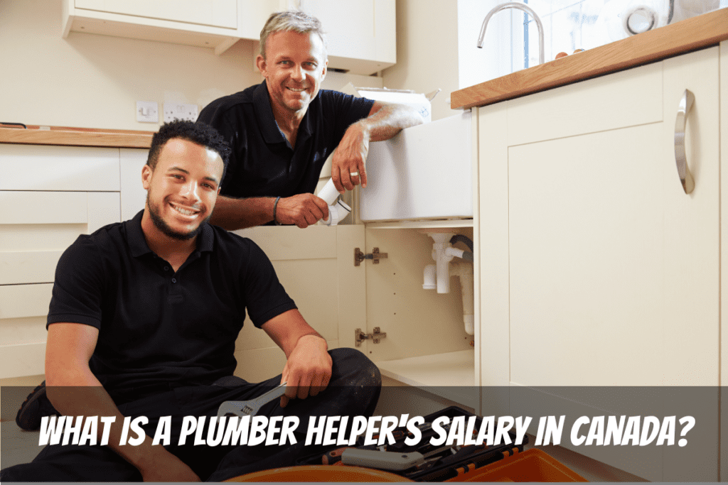 Dos trabajadores sonrientes trabajan en tuberías debajo del fregadero de la cocina para ganar el salario de ayudante de plomero en Canadá