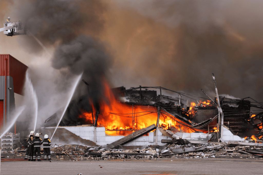 A Large Building Has Collapsed And Is On Fire While Four Firefighter's Tackle The Blaze With Hose Pipes For Firefighter's Salary In Canada