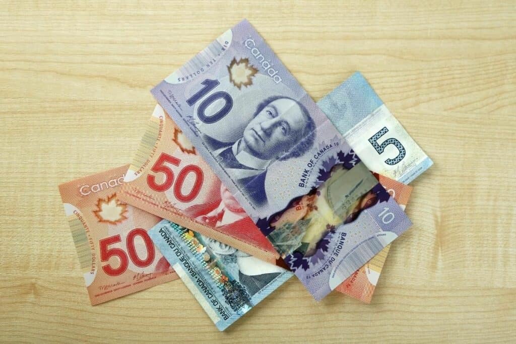 Los billetes de banco canadienses se sientan en una mesa que representa los altos salarios, una de las mejores razones para mudarse a Saskatchewan, Canadá