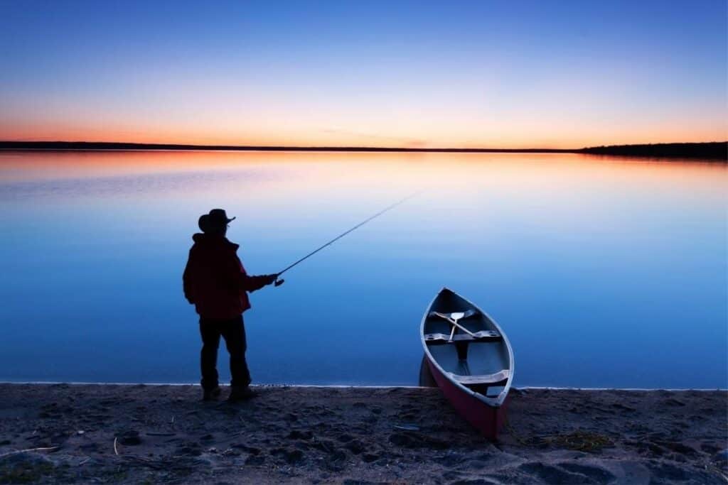 Un pescador pesca desde la playa al borde de un lago cerca de Prince Alberta, una de las mejores razones para mudarse a Saskatchewan, Canadá