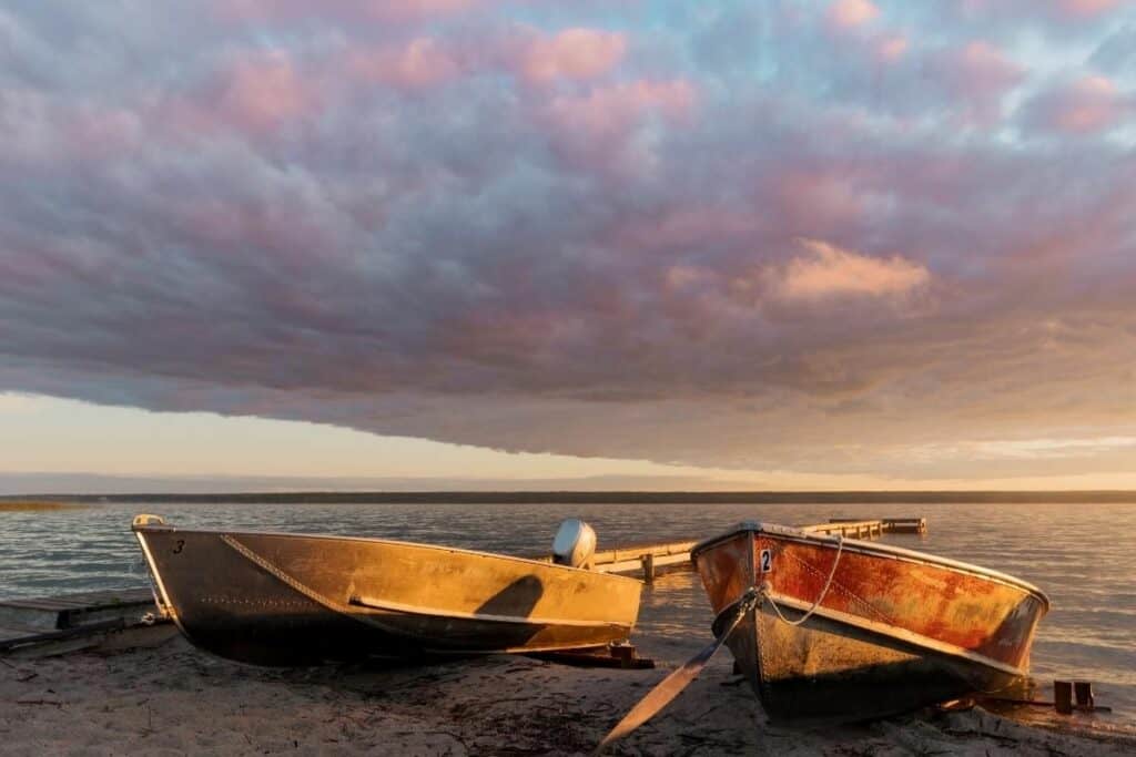 Deux bateaux au bord du lac Meadow avec un ciel dramatique, l'une des meilleures raisons de déménager en Saskatchewan Canada